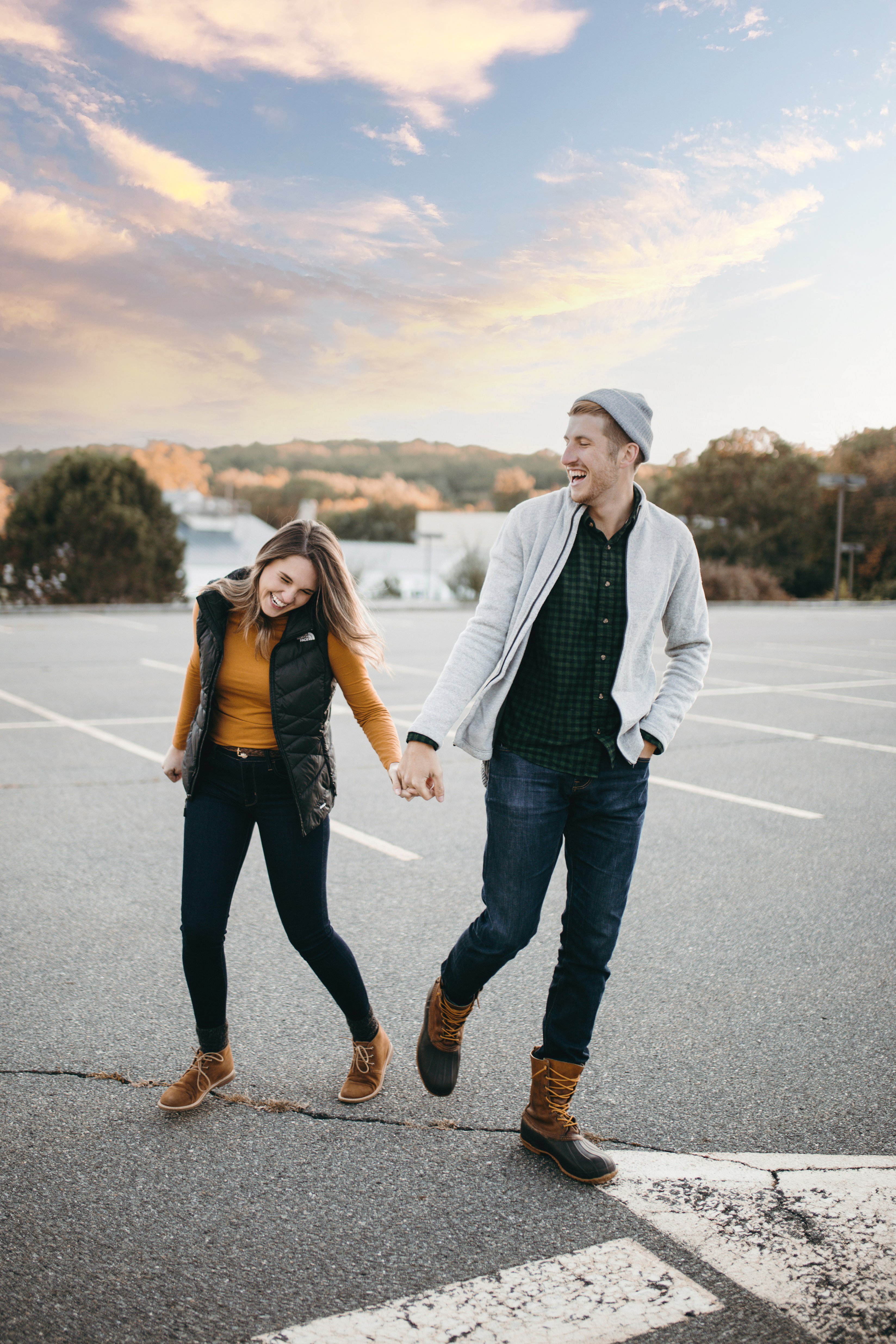 Young couple holding hands in a parking lot at sunset